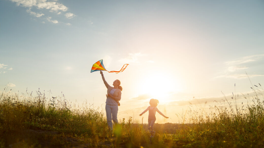 Happy family running through field with kite