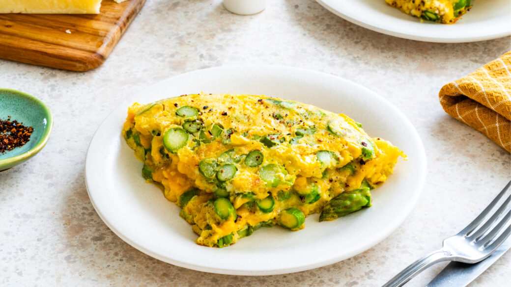 Asparagus omlette breakfast plated on neutral table.
