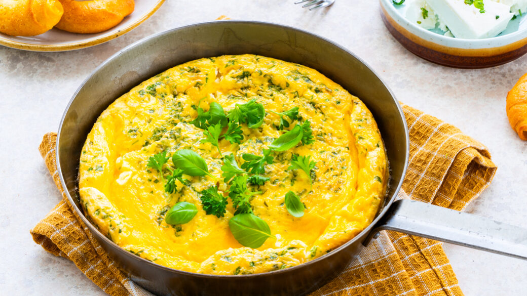Frittata s svežimi zelišči in sirom na jedilni mizi.