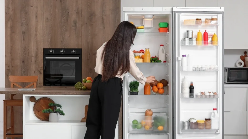 Eine Frau von hinten an einem offenen Smart-Kühlschrank.