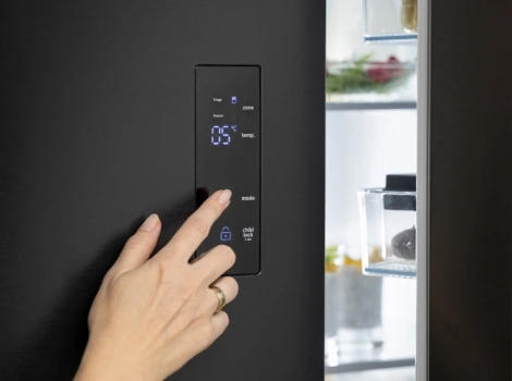 Person stellt etwas an einem schwarzen Smart-Kühlschrank ein.