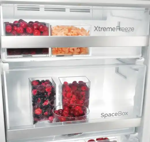 Ein offenes Gefrierfach mit Schubladen und Obst und Gemüse in Boxen.
