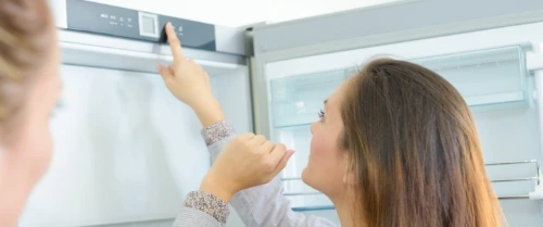 Eine Frau stellt Einstellung am smarten Kühlschrank ein.